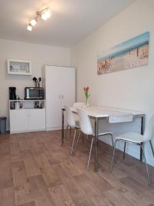 a dining room with a table and white chairs at Ferienwohnung Einfeld in Neumünster