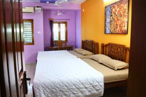 2 łóżka w pokoju z fioletowymi i żółtymi ścianami w obiekcie Bluetique Beach House w mieście Auroville