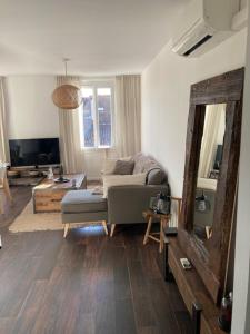 a living room with a couch and a mirror at Lumineux T3 avec vue Mer dans le Centre Historique in Sainte-Maxime