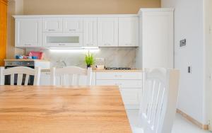 a kitchen with white cabinets and a wooden table at Villetta Maredoro - Fronte Spiaggia Pescoluse in Marina di Pescoluse