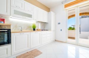 uma cozinha branca com armários brancos e uma janela em Villetta Maredoro - Fronte Spiaggia Pescoluse em Marina di Pescoluse