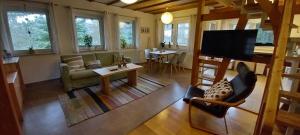 a living room with a couch and a tv and a table at Ferienhaus "Am Schleifenbach" in Saalfeld