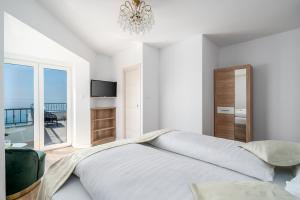 - une chambre blanche avec un grand lit et un balcon dans l'établissement Rooms Vedrana, à Podstrana