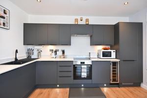 a kitchen with black cabinets and a microwave at Spacious Designer 2BR Executive Apt, Near Beach & Marina, Central Location in Kent