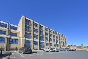 ein großes Gebäude mit auf einem Parkplatz abgestellten Autos in der Unterkunft Spacious Designer 2BR Executive Apt, Near Beach & Marina, Central Location in Kent