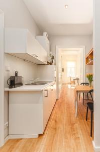 cocina con armarios blancos y suelo de madera en Luxurious and Bright, 5 min to city center, en Viena