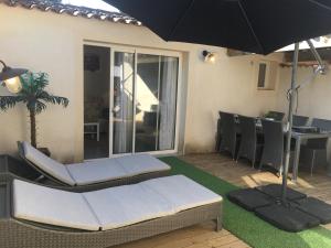 a patio with chairs and an umbrella and a table at Bastidon des Alpilles 11 in Saint-Rémy-de-Provence