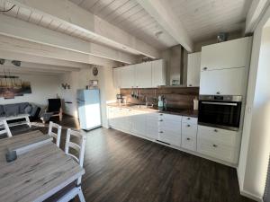 uma cozinha com armários brancos, uma mesa e um frigorífico em Ragnar Maisonette em Büsum