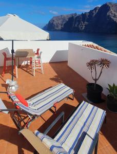 eine Terrasse mit 2 Liegestühlen und einem Sonnenschirm in der Unterkunft Penthouse de Roca in Poblado Marinero in Santiago del Teide