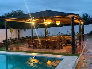 - un pavillon avec une table et des chaises à côté de la piscine dans l'établissement El Rincón del Brillante, à Cordoue
