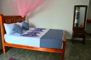 a bed with blue and white sheets and a mirror at Ella Infinity View in Ella