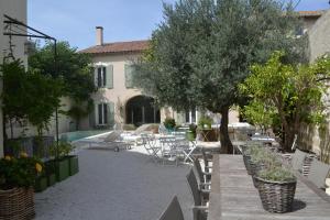 un patio con mesas, sillas y árboles y un edificio en Mas À l'Improviste, en Saint-Rémy-de-Provence