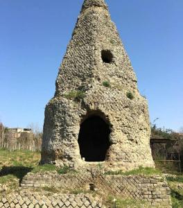 un antiguo edificio de piedra con una torre en un campo en Casa Flegrea Napoli, en Quarto