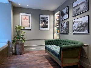 sala de estar con sofá verde y cuadros en la pared en AZ Hotel San Valero, en Zaragoza