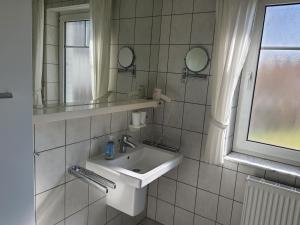 La salle de bains blanche est pourvue d'un lavabo et d'un miroir. dans l'établissement Darsser Weg 32, à Zingst
