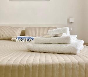 une pile de serviettes blanches assises au-dessus d'un lit dans l'établissement La dimora di Clara, à Trapani