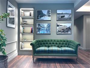 a green couch in a living room with pictures on the wall at AZ Hotel San Valero in Zaragoza