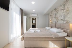 a bedroom with a large bed with white pillows at HARMONY Stay APARTAMENTAI su terasa ir vaizdu į miestą in Telšiai
