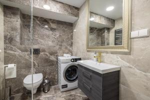 a bathroom with a washing machine and a washer and dryer at HARMONY Stay APARTAMENTAI su terasa ir vaizdu į miestą in Telšiai