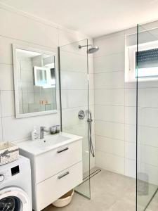 een witte badkamer met een wastafel en een douche bij Brand new 3 bedroom apartment Inara G in Nin