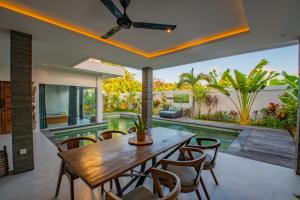 comedor al aire libre con mesa de madera y sillas en Hedonia Luxury Villas, en Seminyak