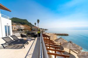 a balcony with chairs and umbrellas next to the ocean at Rooms Vedrana in Podstrana