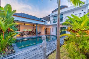 Villa con una estatua frente a la piscina en Hedonia Luxury Villas, en Seminyak