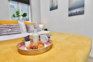 a tray of croissants and a plate of food on a bed at Daimler House - Cosy Home Near Coventry City Centre in Coventry
