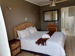 a bedroom with a bed with white sheets and a mirror at Tushiya guest lodge witbank in eMalahleni
