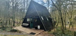 a black house with a green door in the woods at Chalet 146 Arrivée in Durbuy
