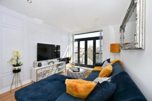 ein Wohnzimmer mit einem blauen Sofa und einem Fernseher in der Unterkunft Spacious Designer 2BR Executive Apt, Near Beach & Marina, Central Location in Kent