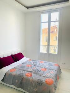 een bed in een witte kamer met een raam bij Villa cadette, à 200m de monaco in Beausoleil