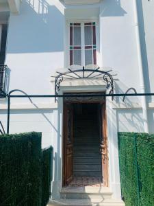 een wit huis met een houten deur en trap bij Villa cadette, à 200m de monaco in Beausoleil