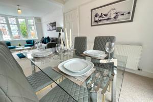 3Bed Coventry Gem - The Perfect Home Away From Home في كوفينتري: غرفة طعام مع طاولة وكراسي زجاجية