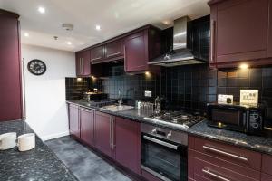 cocina con armarios morados y horno con fogones en The Arran Suite - Your Stylish Scottish Getaway! en Glasgow