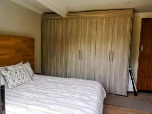a bedroom with a large white bed and wooden cabinets at Rest-a-While Guest House - Pretoria in Pretoria