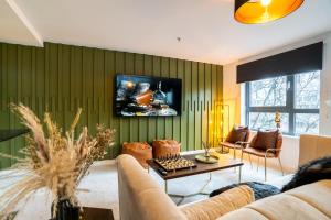 a living room with a couch and a tv on a wall at The Arran Suite - Your Stylish Scottish Getaway! in Glasgow