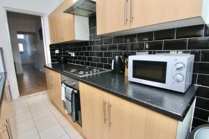 a kitchen with a microwave on top of a counter at Tranquil 3Bed Retreat - Walk to Coventry University, Fargo Village & Coventry City Centre in Coventry