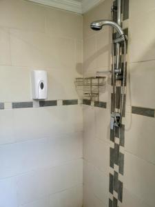 a shower with a shower head in a bathroom at Rest-a-While Guest House - Pretoria in Pretoria