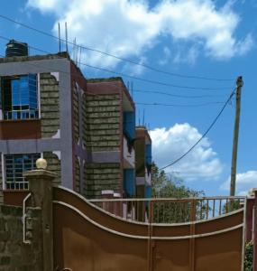 una valla frente a un edificio con una puerta en Megs Place - Red - Embu Town, en Embu