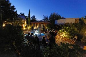a group of people sitting at a table in a garden at night at Appartement T1 "Capella" de l'observatoire in Bauduen