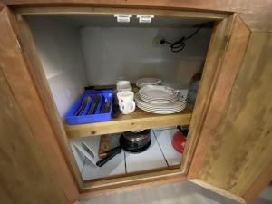 a small cabinet with plates and dishes in it at Pacheco Tours Rainforest Cabins in Drake