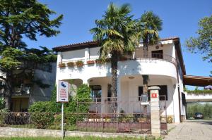 a white house with a palm tree in front of it at Apartments Bertok in Koper