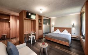 ein Hotelzimmer mit einem Bett und einem Sofa in der Unterkunft La Paula Apartments & Suites in Seis am Schlern