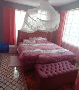 una camera con letto rosa a baldacchino di Megs Place - Red - Embu Town a Embu