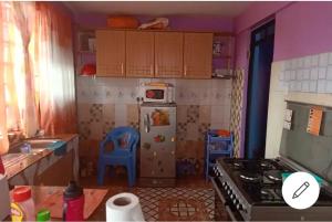 a small kitchen with a refrigerator and a stove at Megs Place - Red - Embu Town in Embu