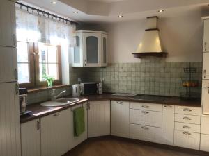 a kitchen with white cabinets and a sink and a window at Dom za Wydmą in Rogowo