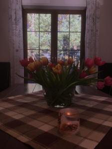 a vase of tulips on a table with a candle at Dom za Wydmą in Rogowo