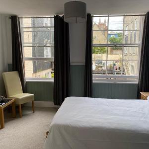 um quarto com uma cama, uma cadeira e janelas em King William IV em Totnes