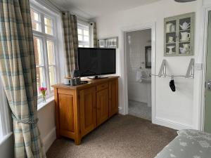 a television on a wooden cabinet in a bathroom at King William IV in Totnes +11 photos